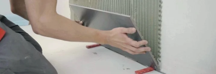 Person bringt Fliese an Wand an